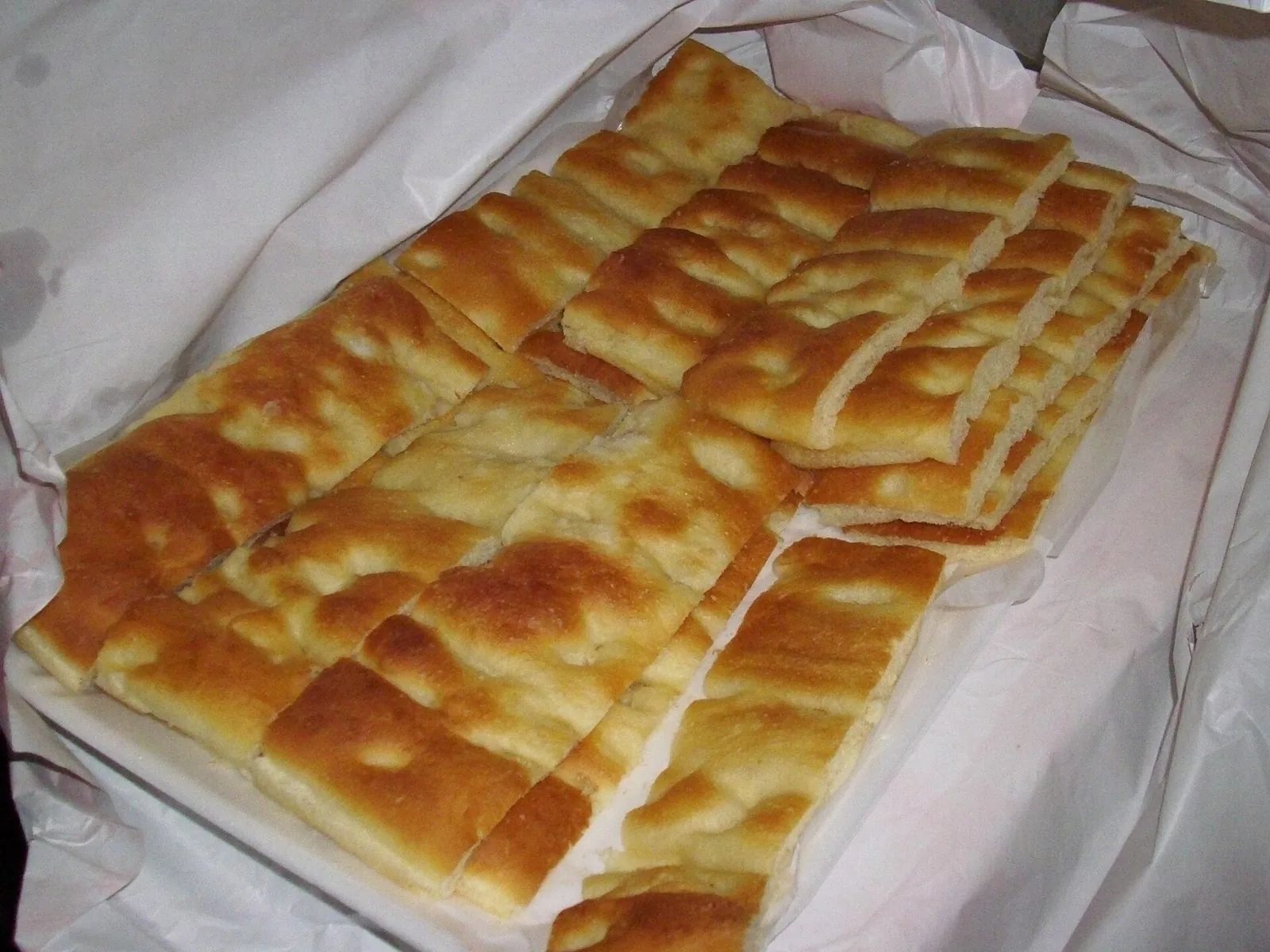 Focaccia genovese dorata tagliata a strisce su carta da forno