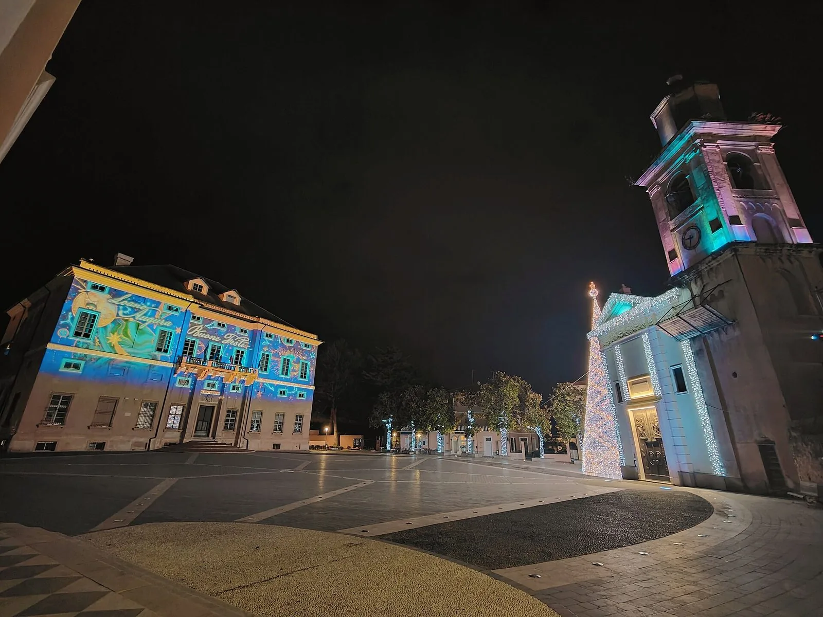 Piazza Italia a Loano di notte nel periodo natalizio, con l'albero di luci e Palazzo Doria illuminato da proiezioni