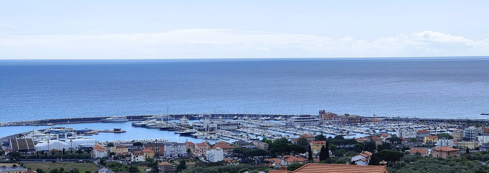 Il porto turistico di Loano visto dalla collina con il mare calmo e il cielo velato